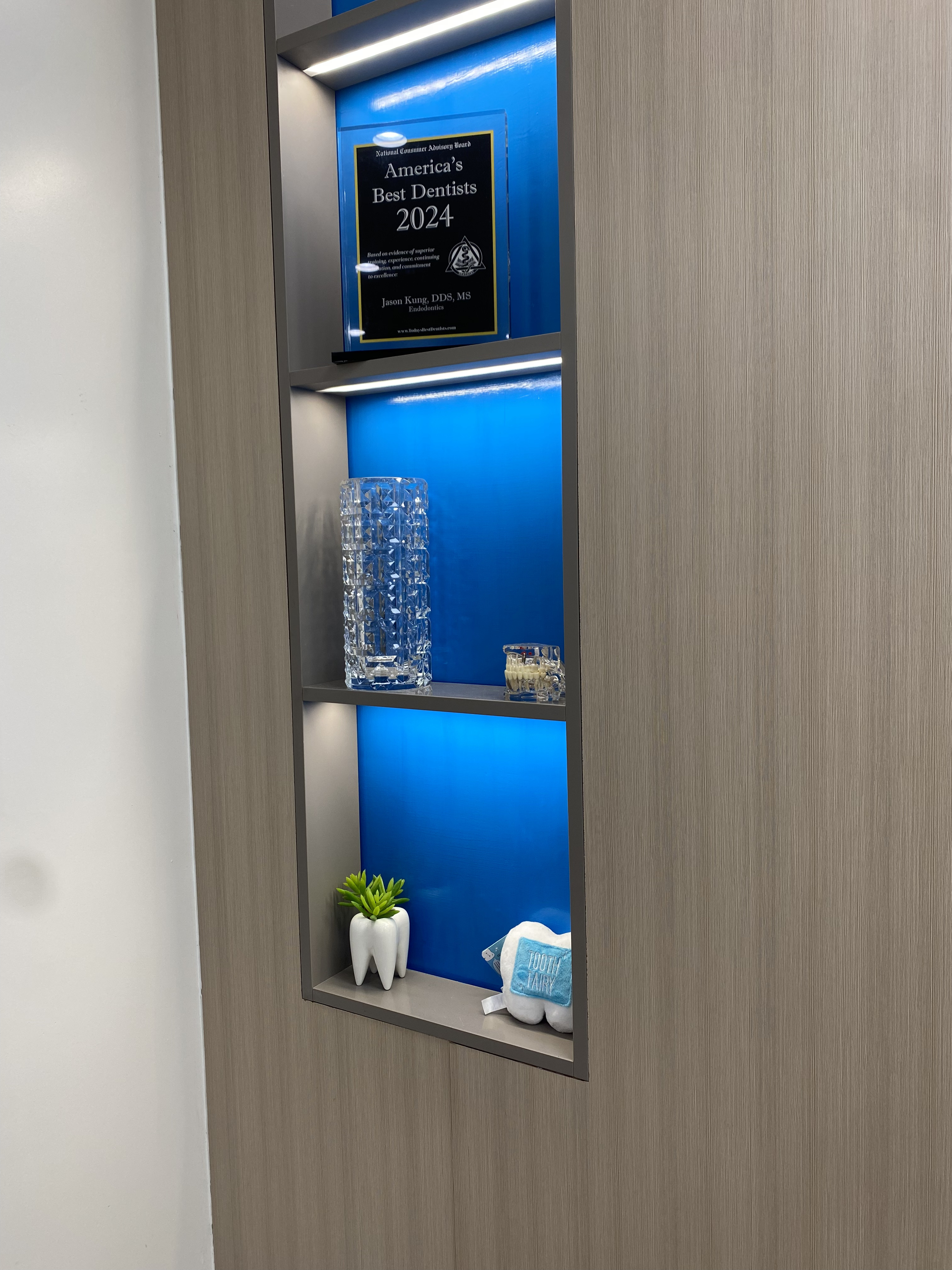 Blue-lit display shelf showing the America's Best Dentists 2024 award plaque awarded to Dr. Jason Kung