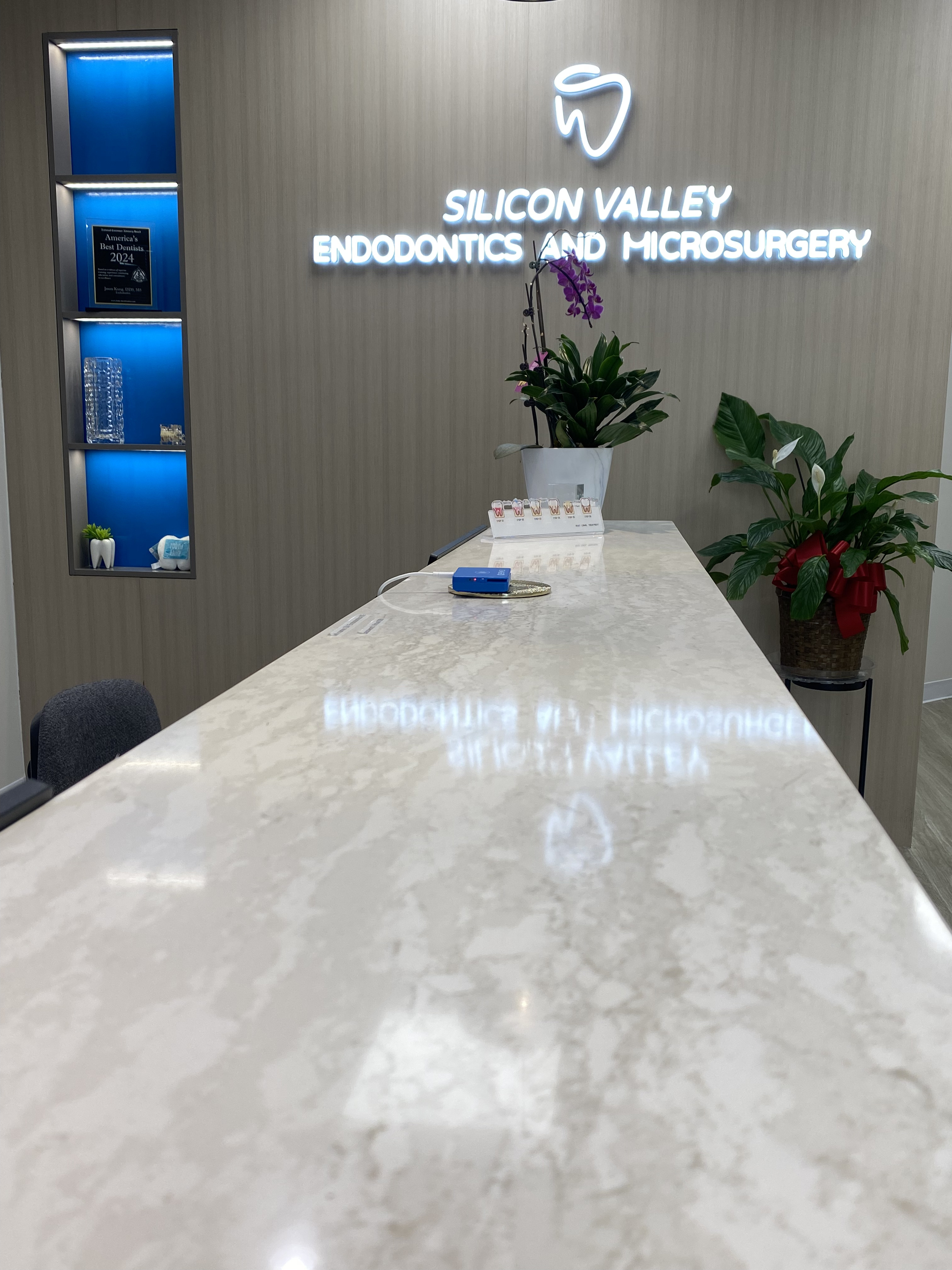 Close-up of the marble reception desk with the illuminated Silicon Valley Endodontics sign reflected on the surface