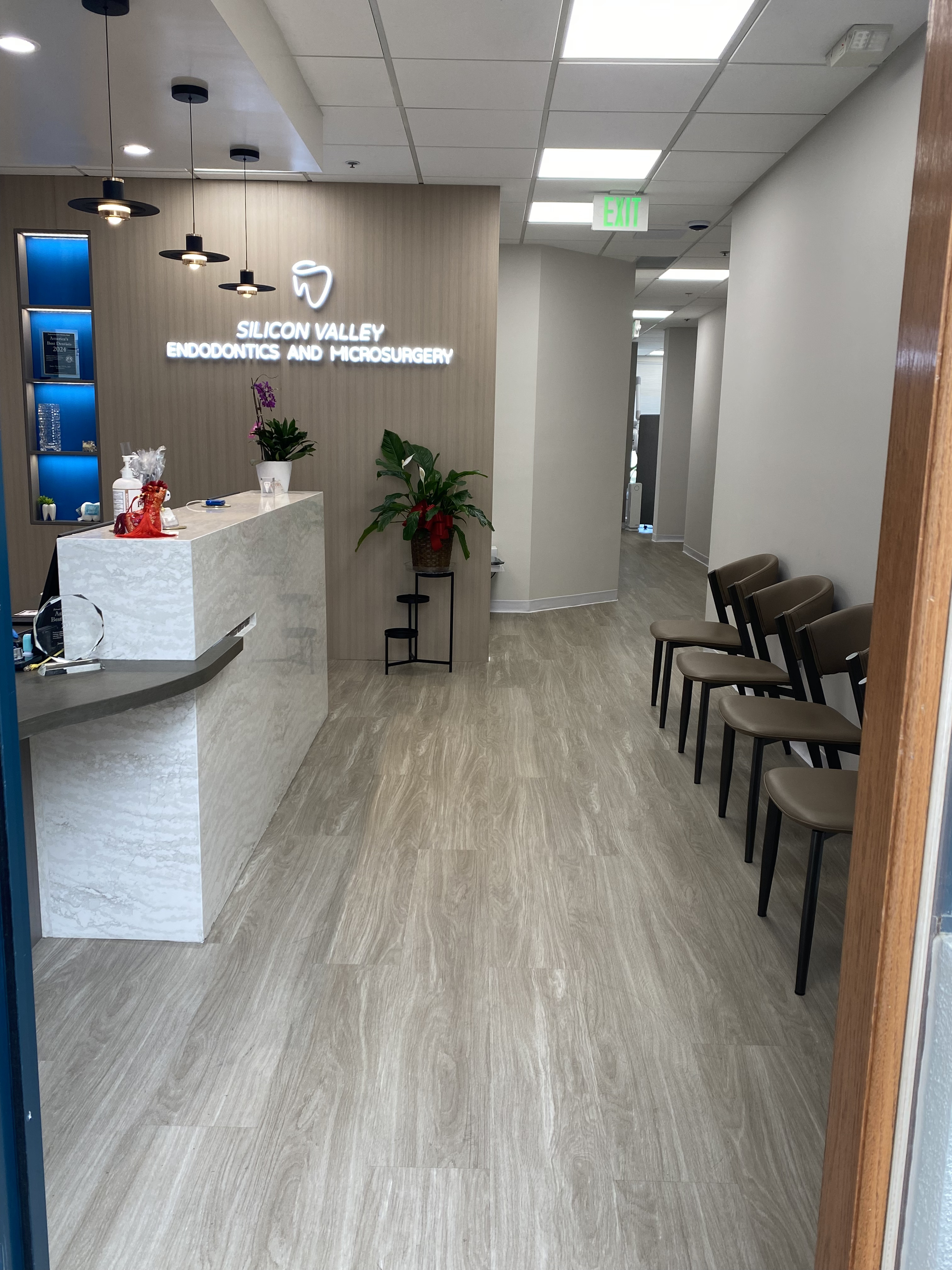 Spacious waiting area with modern chairs, hardwood floors, and reception desk visible in the background