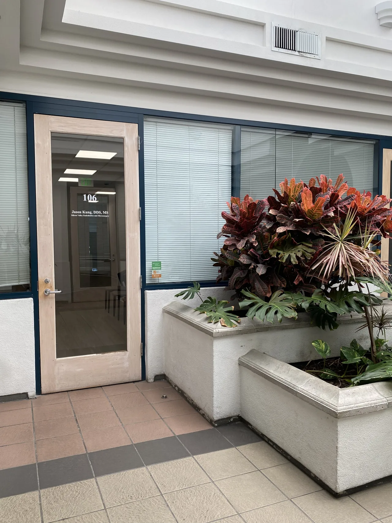 Exterior of the building at 1565 Hollenbeck Avenue, Sunnyvale — landscaped entrance with planters leading to Suite 106