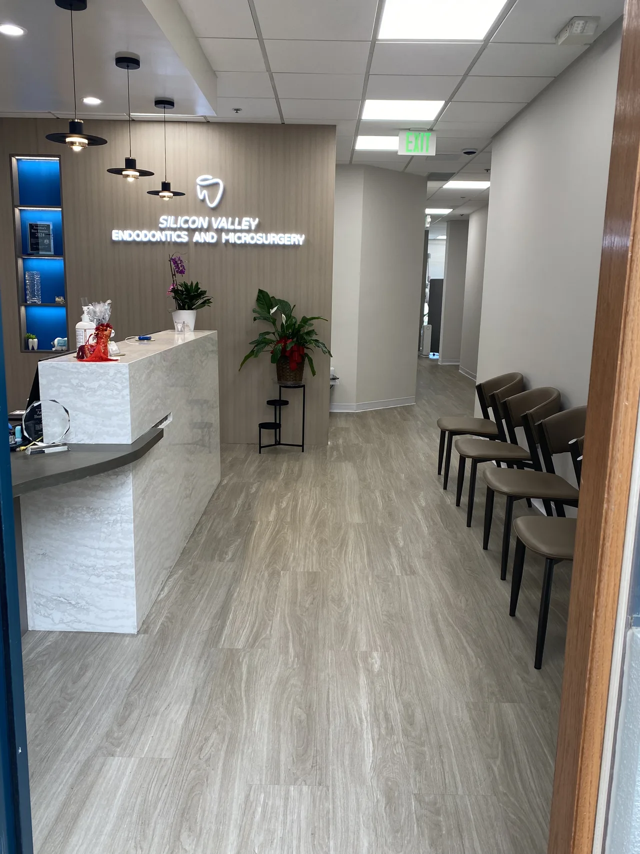 Reception and waiting area at Silicon Valley Endodontics and Microsurgery in Sunnyvale, with backlit signage and contemporary seating.